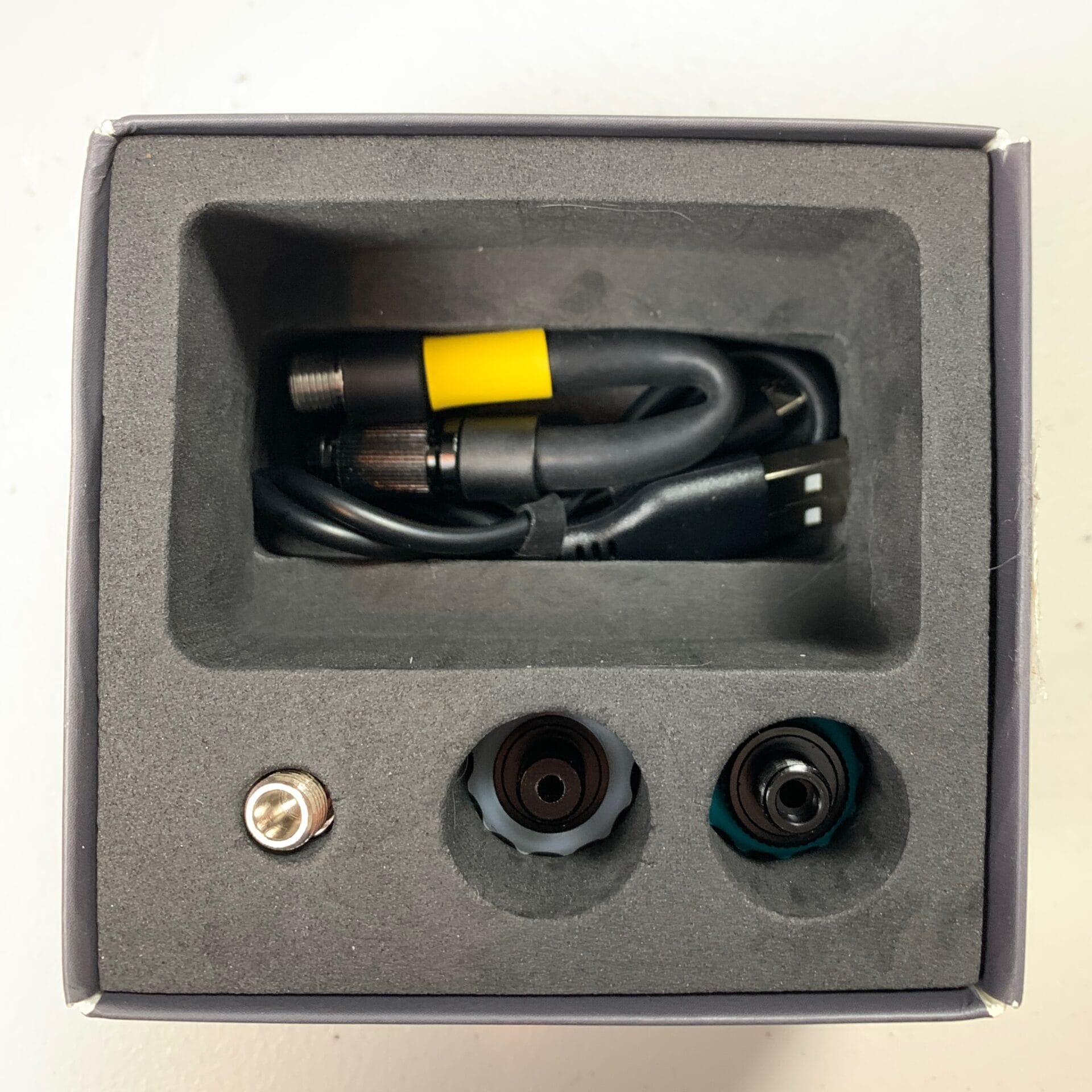 Charge cable and hose visible at the bottom of the box