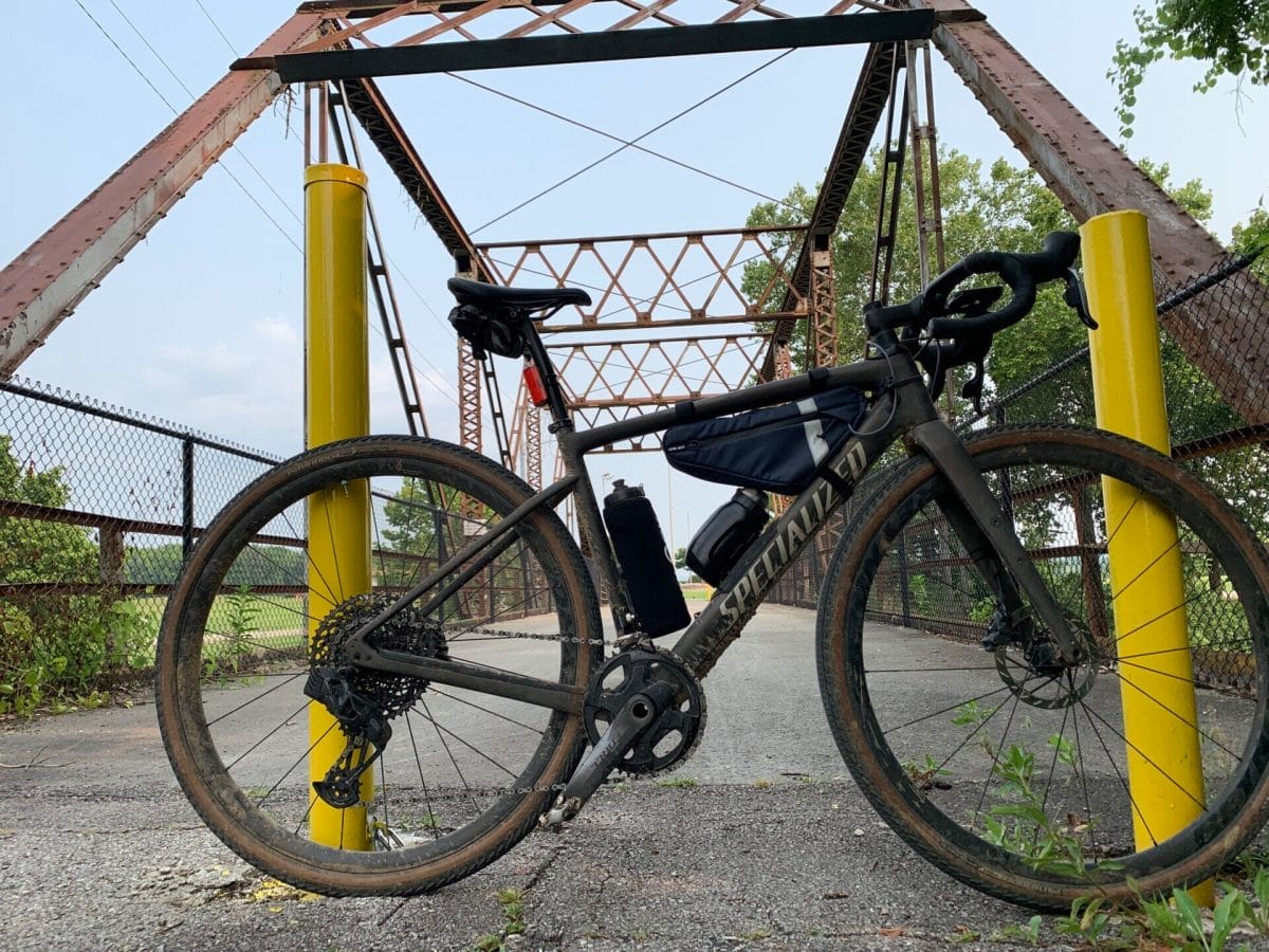 Gravel bike with frame bag on with smaller Fidlock bottle installed on bike. Bridge in background