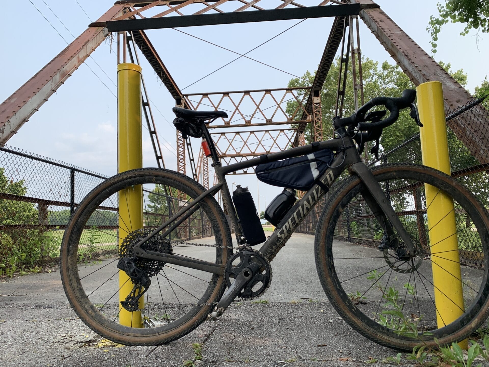 Gravel bike with frame bag on with smaller Fidlock bottle installed on bike. Bridge in background